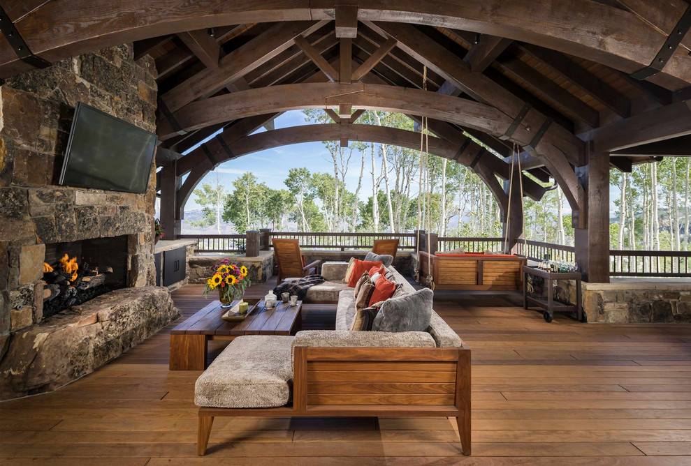 Inspiration for a rustic deck remodel with a fireplace and a roof extension
