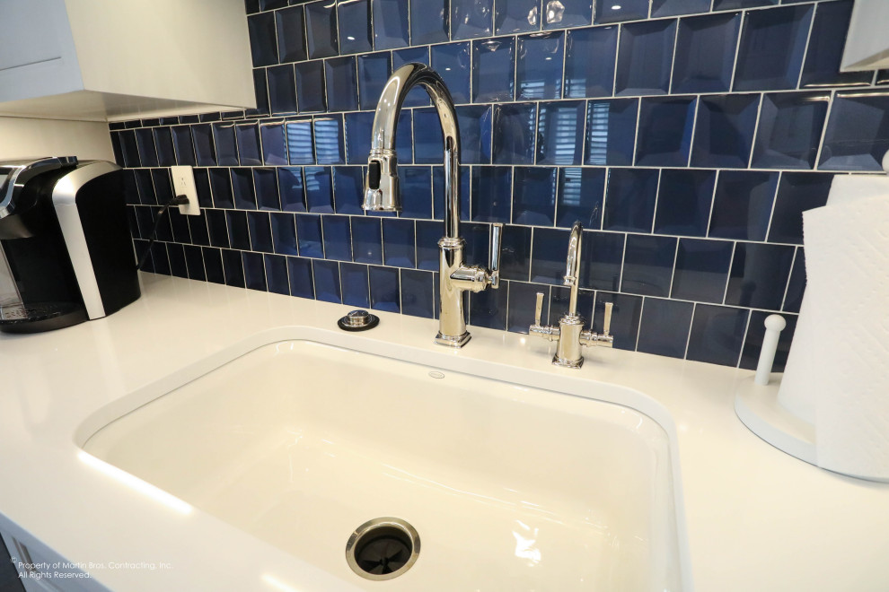 Example of a mid-sized transitional u-shaped medium tone wood floor open concept kitchen design with a single-bowl sink, flat-panel cabinets, white cabinets, quartz countertops, blue backsplash, glass tile backsplash, stainless steel appliances, an island and white countertops