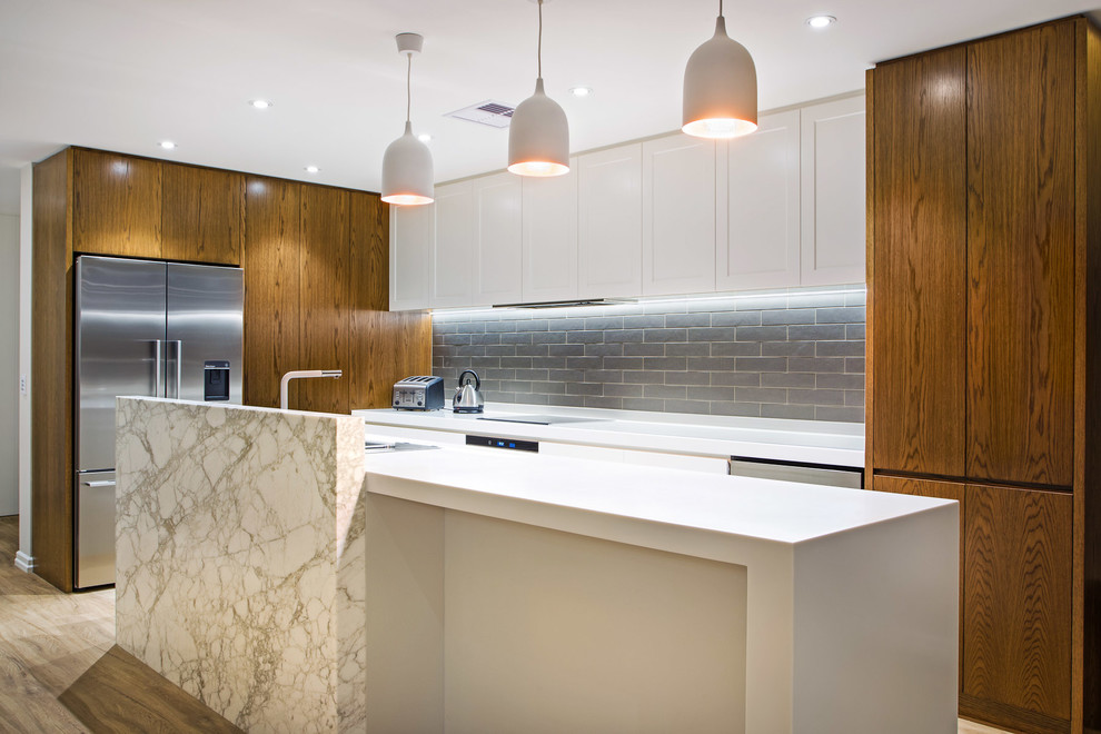 Inspiration for a mid-sized beach style galley open plan kitchen in Brisbane with an undermount sink, flat-panel cabinets, medium wood cabinets, quartz benchtops, grey splashback, subway tile splashback, stainless steel appliances, vinyl floors and with island.