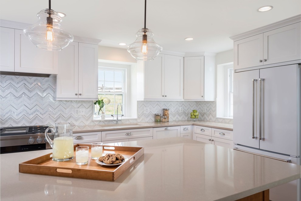 This is an example of a mid-sized transitional l-shaped eat-in kitchen in DC Metro with an undermount sink, shaker cabinets, white cabinets, laminate benchtops, metallic splashback, ceramic splashback, white appliances, with island and brown floor.