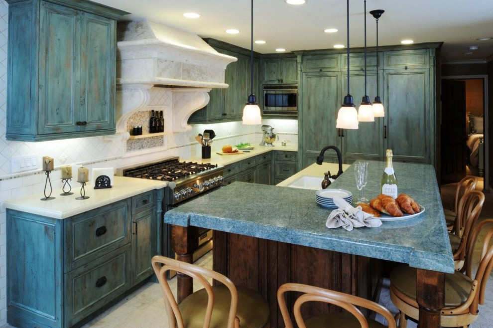 Example of a mid-sized french country l-shaped limestone floor and beige floor open concept kitchen design in Los Angeles with an undermount sink, recessed-panel cabinets, distressed cabinets, granite countertops, white backsplash, ceramic backsplash, paneled appliances, an island and green countertops