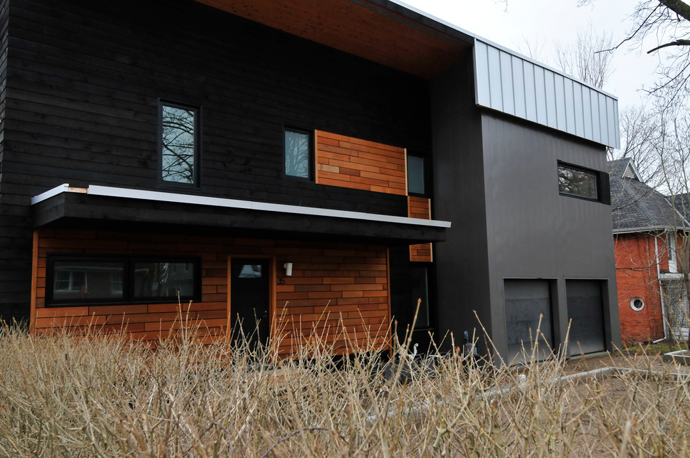 Mid-sized modern two-storey black exterior in Toronto with metal siding and a flat roof.