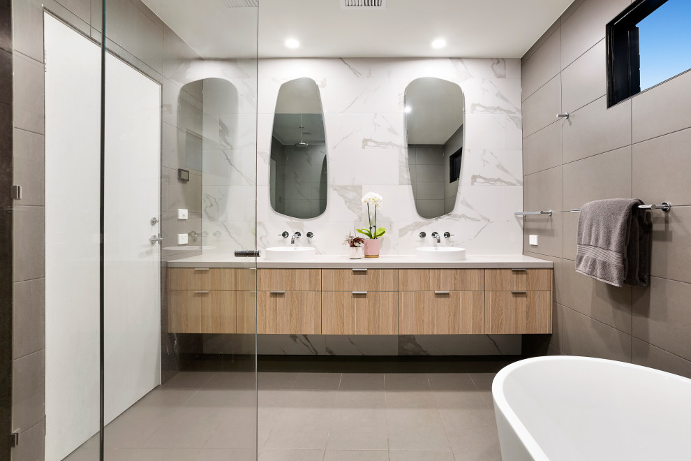 Contemporary master bathroom in Melbourne with flat-panel cabinets, light wood cabinets, a freestanding tub, white tile, a vessel sink, grey floor, white benchtops, a double vanity and a floating vanity.