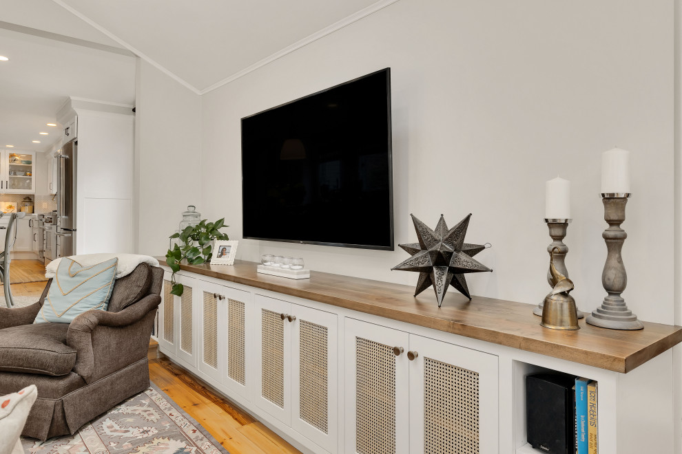 Ispirazione per un grande soggiorno chic con pareti beige, parquet chiaro e TV a parete