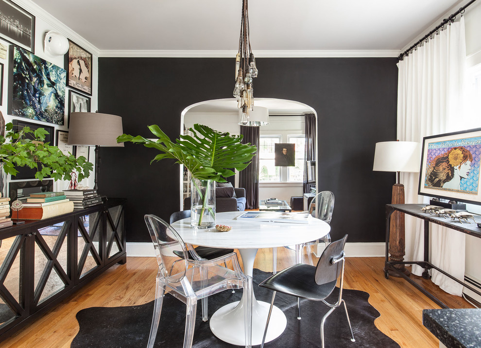 Eclectic dining room in New York with black walls, medium hardwood floors and brown floor.