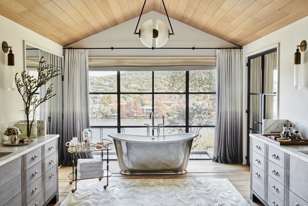 Example of an eclectic medium tone wood floor freestanding bathtub design in Austin