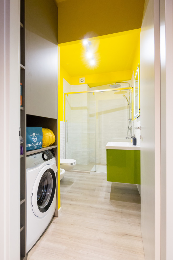 This is an example of a small contemporary 3/4 bathroom in Milan with green cabinets, white tile, porcelain tile, yellow walls, solid surface benchtops, flat-panel cabinets, an alcove shower, a wall-mount toilet, light hardwood floors, a console sink, beige floor, a sliding shower screen and white benchtops.