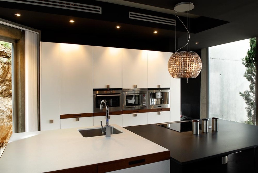 Inspiration for a large contemporary single-wall open plan kitchen in Alicante-Costa Blanca with an undermount sink, flat-panel cabinets, white cabinets, quartz benchtops, brown splashback, slate splashback, stainless steel appliances, dark hardwood floors, with island, brown floor and black benchtop.