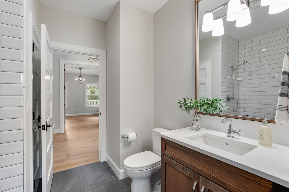 Photo of a mid-sized transitional 3/4 bathroom in Portland with shaker cabinets, medium wood cabinets, an open shower, a one-piece toilet, white tile, ceramic tile, grey walls, ceramic floors, a drop-in sink, engineered quartz benchtops, grey floor, an open shower, white benchtops, a niche, a single vanity and a built-in vanity.