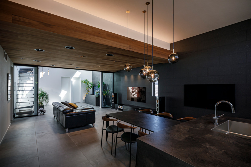 Modern inredning av ett stort öppen hemmabio, med svarta väggar, klinkergolv i porslin, en väggmonterad TV och grått golv