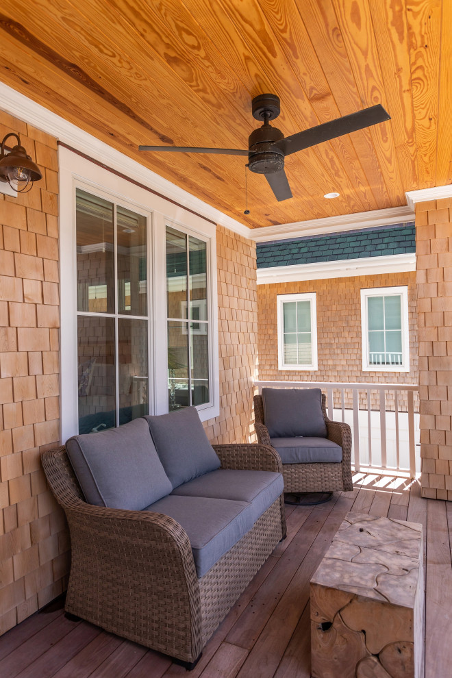 This is an example of an expansive beach style back metal railing veranda in Wilmington with a roof extension.