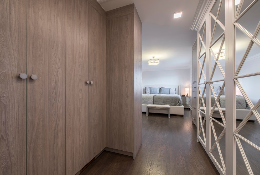 This is an example of a large contemporary women's walk-in wardrobe in Toronto with flat-panel cabinets, medium wood cabinets, medium hardwood floors and brown floor.