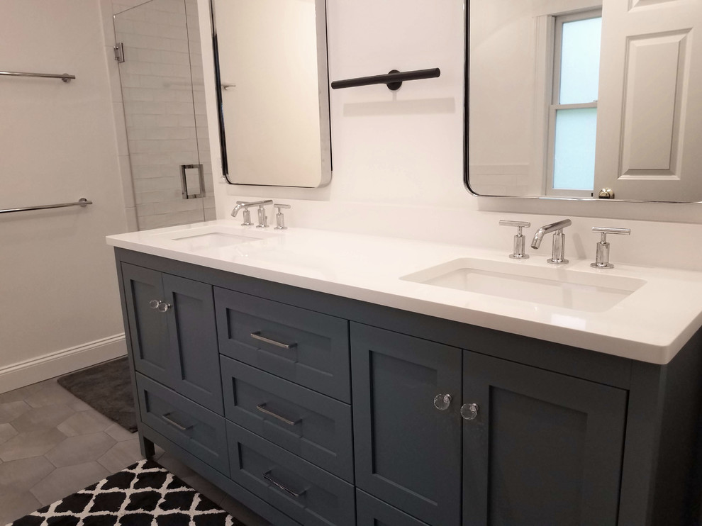 This is an example of a mid-sized transitional master bathroom in Boston with recessed-panel cabinets, blue cabinets, a freestanding tub, an alcove shower, a two-piece toilet, white tile, subway tile, grey walls, ceramic floors, an undermount sink, quartzite benchtops, grey floor, a hinged shower door and white benchtops.