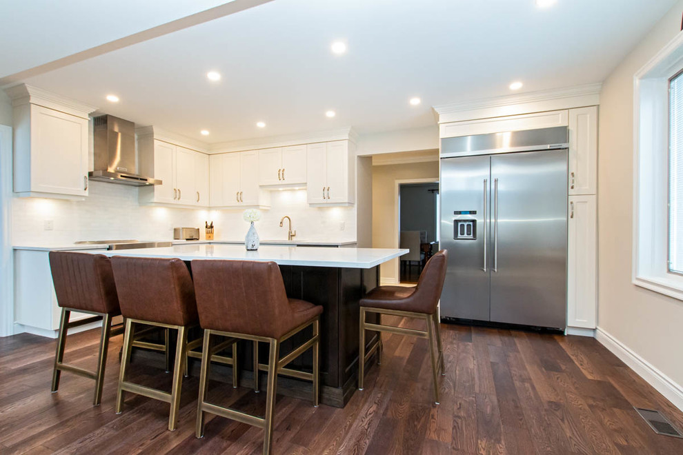 Inspiration for a mid-sized transitional l-shaped medium tone wood floor and brown floor open concept kitchen remodel with an undermount sink, shaker cabinets, white cabinets, quartzite countertops, white backsplash, stone tile backsplash, stainless steel appliances, an island and white countertops