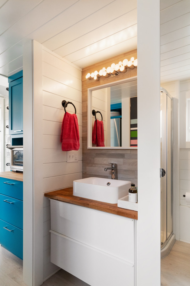 This is an example of a small beach style bathroom in Philadelphia with flat-panel cabinets, white cabinets, vinyl floors, wood benchtops, an enclosed toilet, a single vanity, a floating vanity, timber and planked wall panelling.