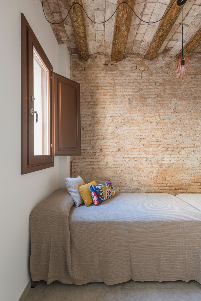 Réalisation d'une grande chambre d'amis minimaliste avec un mur blanc, un sol en carrelage de céramique, un sol beige, poutres apparentes et un mur en parement de brique.