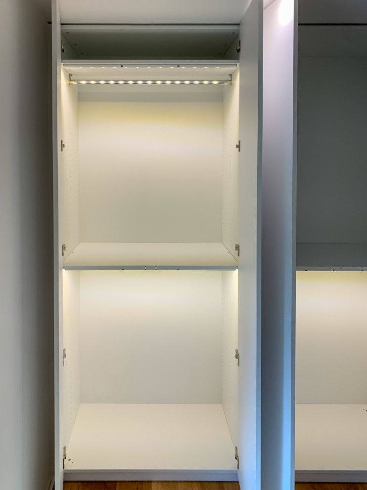 This is an example of a large contemporary dressing room in Munich with flat-panel cabinets, white cabinets, medium hardwood floors and brown floor.