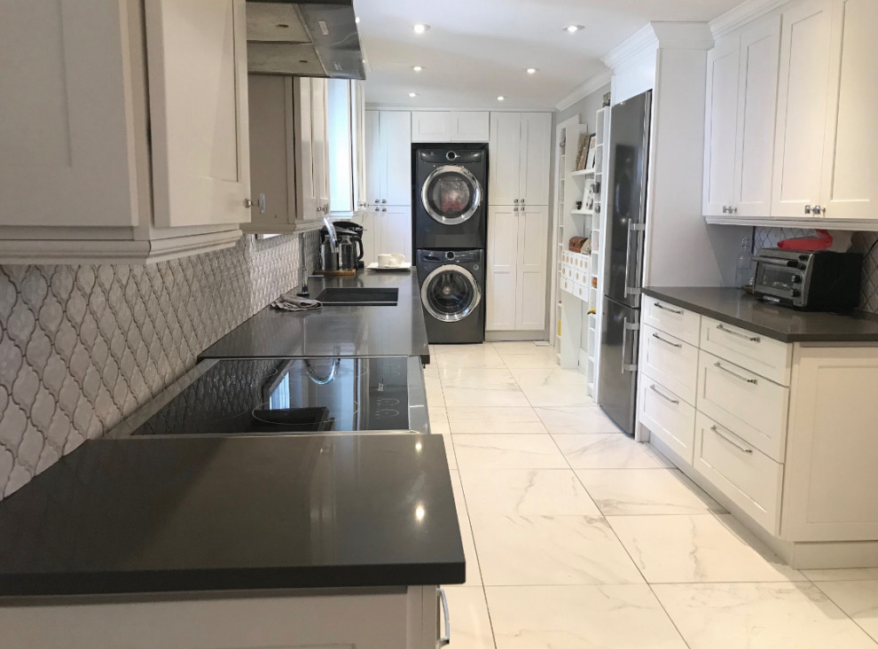Inspiration for a large transitional galley marble floor and white floor enclosed kitchen remodel with an undermount sink, shaker cabinets, white cabinets, quartz countertops, white backsplash, porcelain backsplash, stainless steel appliances and gray countertops
