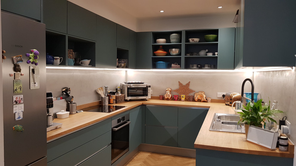 Mid-sized contemporary u-shaped separate kitchen in London with flat-panel cabinets, green cabinets, wood benchtops, grey splashback, light hardwood floors and no island.