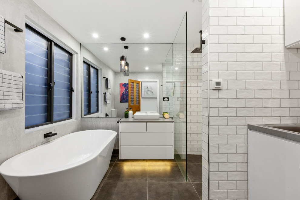 Inspiration for a contemporary bathroom in Melbourne with flat-panel cabinets, white cabinets, a freestanding tub, white tile, a vessel sink, grey floor, grey benchtops, a single vanity and a built-in vanity.