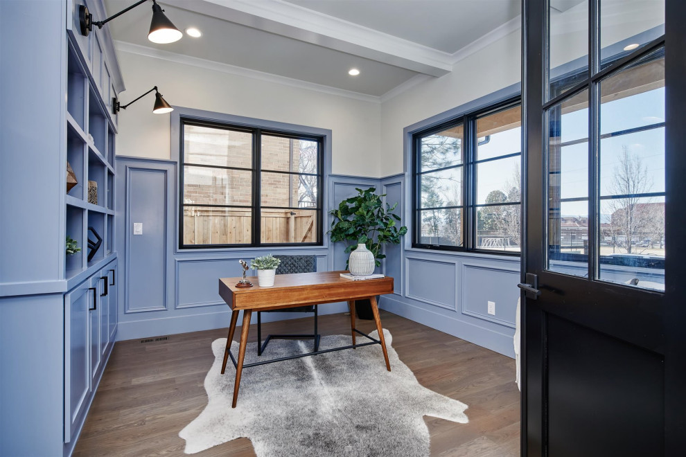 Imagen de despacho de estilo de casa de campo grande con paredes azules, suelo de madera clara, suelo marrón y vigas vistas