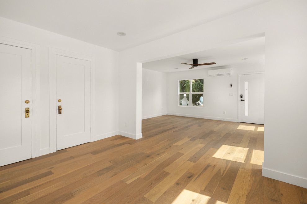 Diseño de distribuidor contemporáneo de tamaño medio con paredes blancas, suelo de madera clara, puerta simple, puerta blanca y suelo marrón
