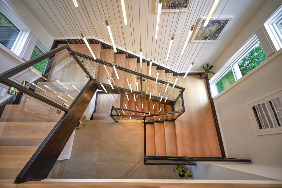 Diseño de escalera en U moderna grande sin contrahuella con escalones de madera y barandilla de metal