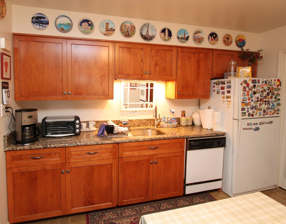 Photo of a transitional l-shaped eat-in kitchen in Baltimore with an undermount sink, recessed-panel cabinets, medium wood cabinets, granite benchtops, white splashback, white appliances, linoleum floors and no island.