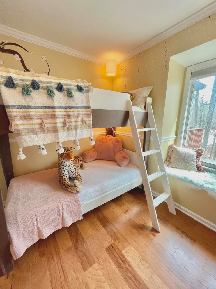 Modelo de dormitorio clásico de tamaño medio con suelo de madera clara y paredes amarillas