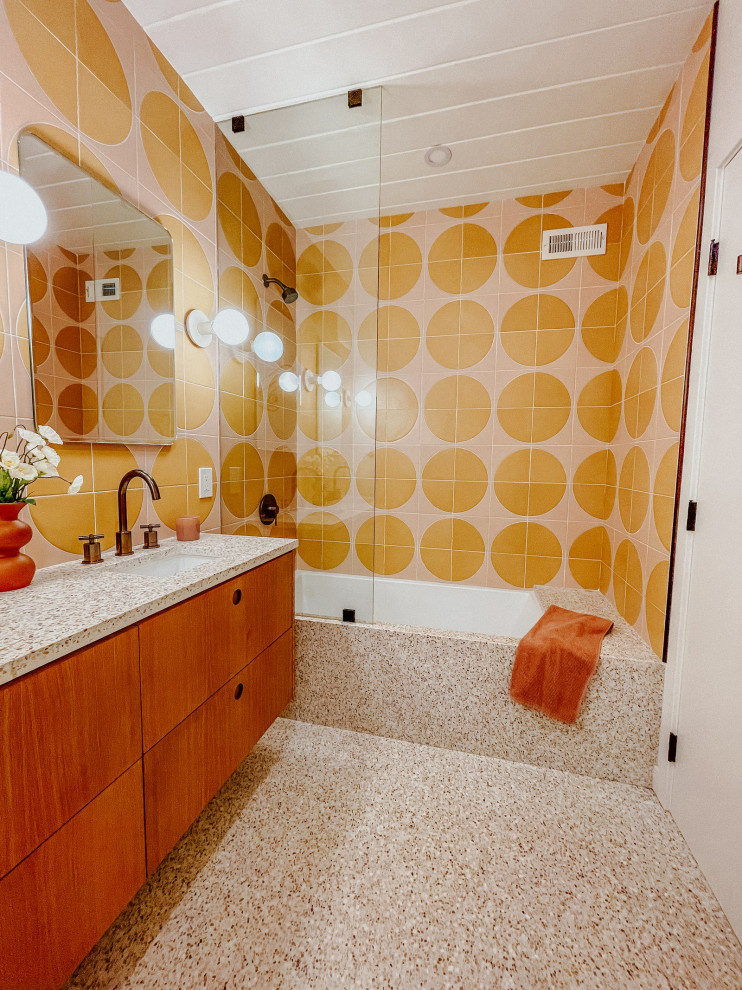 Пример оригинального дизайна: ванная комната среднего размера в стиле ретро с плоскими фасадами, душем над ванной, оранжевой плиткой, цементной плиткой, розовыми стенами, полом из терраццо, душевой кабиной, столешницей терраццо, розовым полом, открытым душем, розовой столешницей, тумбой под одну раковину, напольной тумбой и потолком из вагонки