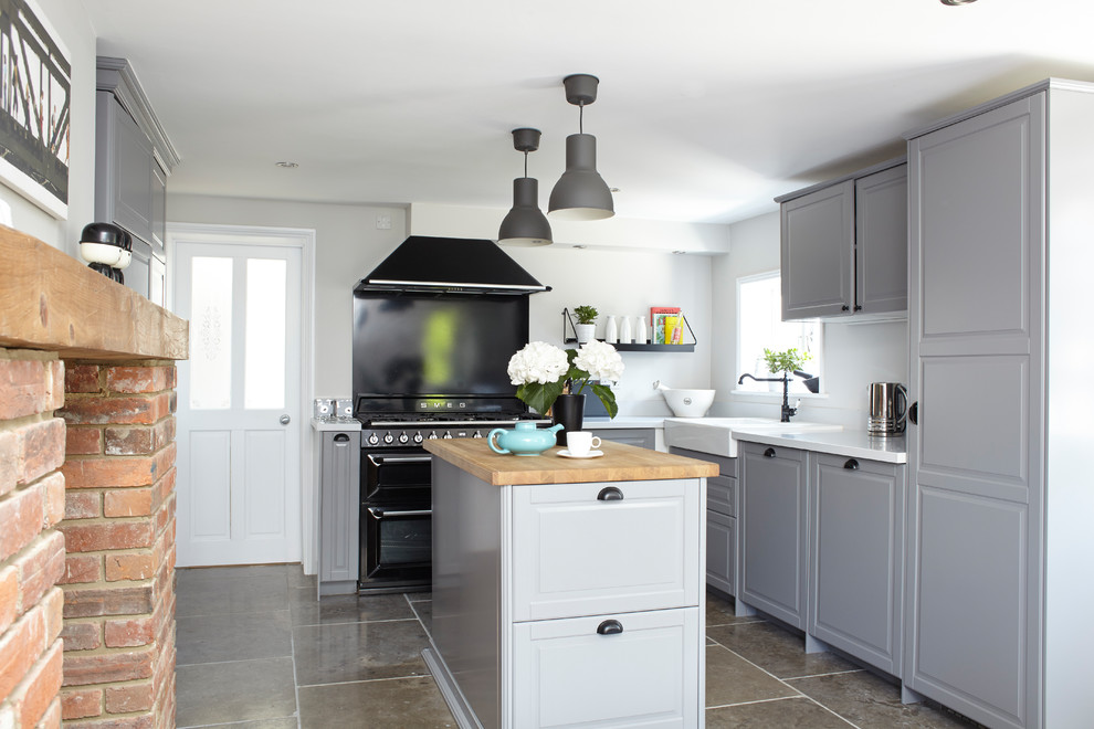 Design ideas for a country l-shaped eat-in kitchen in London with a farmhouse sink, raised-panel cabinets, grey cabinets, quartzite benchtops, with island, grey floor, black splashback and panelled appliances.