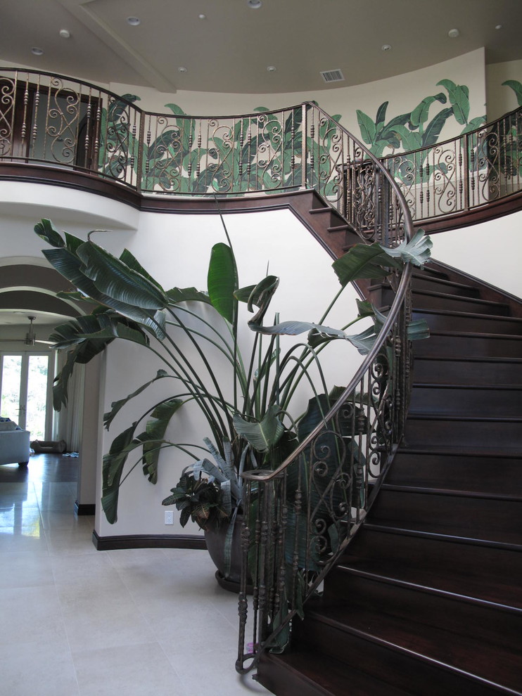 Large tropical wood curved staircase in Los Angeles with wood risers.