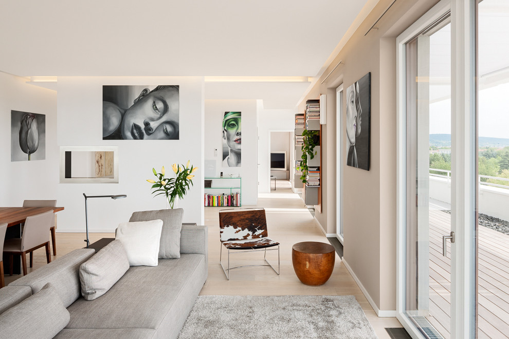 Contemporary open concept family room in Berlin with light hardwood floors and beige walls.