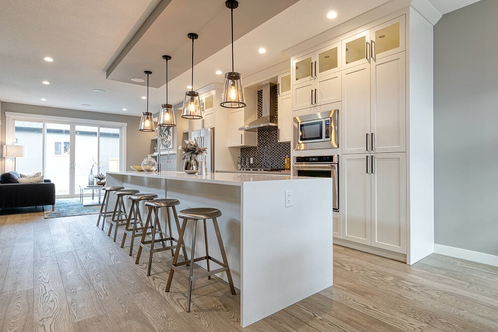 Example of a large transitional u-shaped vinyl floor and gray floor eat-in kitchen design with an undermount sink, recessed-panel cabinets, white cabinets, quartzite countertops, black backsplash, mosaic tile backsplash, stainless steel appliances, an island and white countertops