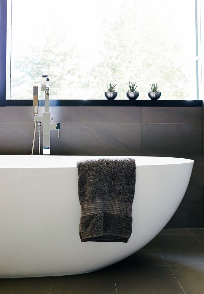 Design ideas for a mid-sized contemporary master bathroom in Vancouver with a vessel sink, flat-panel cabinets, light wood cabinets, engineered quartz benchtops, a freestanding tub, an open shower, a wall-mount toilet, gray tile, porcelain tile, grey walls and porcelain floors.