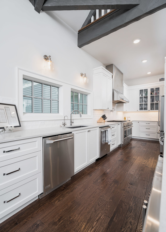 Inspiration for a mid-sized transitional u-shaped dark wood floor and brown floor open concept kitchen remodel with an undermount sink, shaker cabinets, white cabinets, quartz countertops, white backsplash, ceramic backsplash, stainless steel appliances and an island