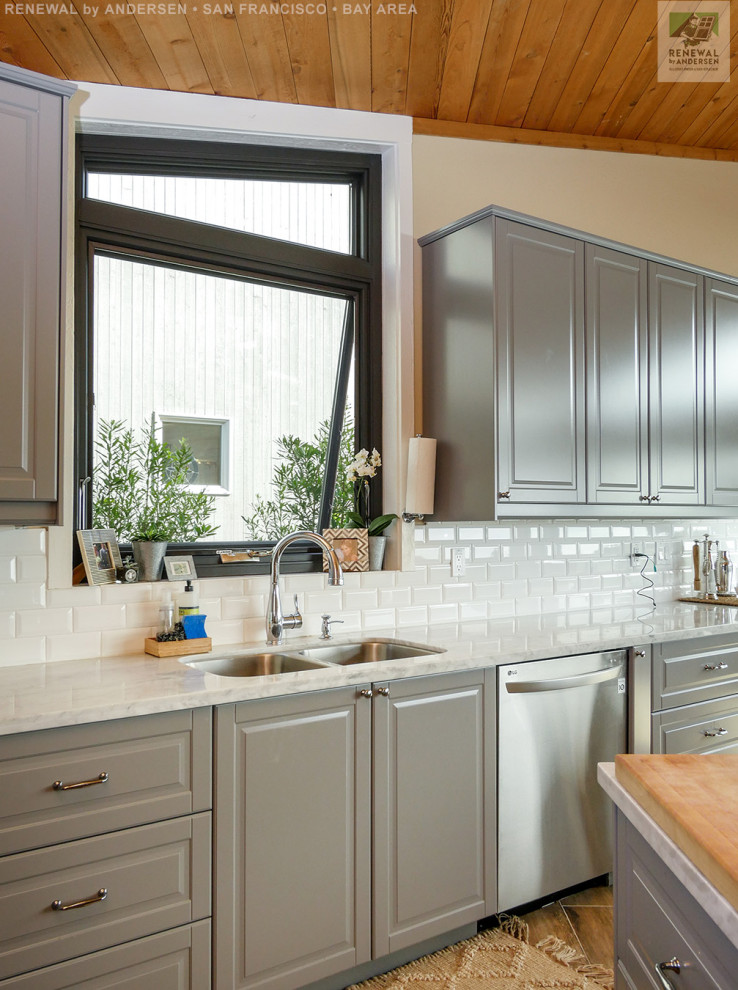 Idéer för mellanstora linjära vitt kök med öppen planlösning, med en undermonterad diskho, grå skåp, bänkskiva i kvarts, vitt stänkskydd, stänkskydd i tunnelbanekakel, rostfria vitvaror, mellanmörkt trägolv och en köksö