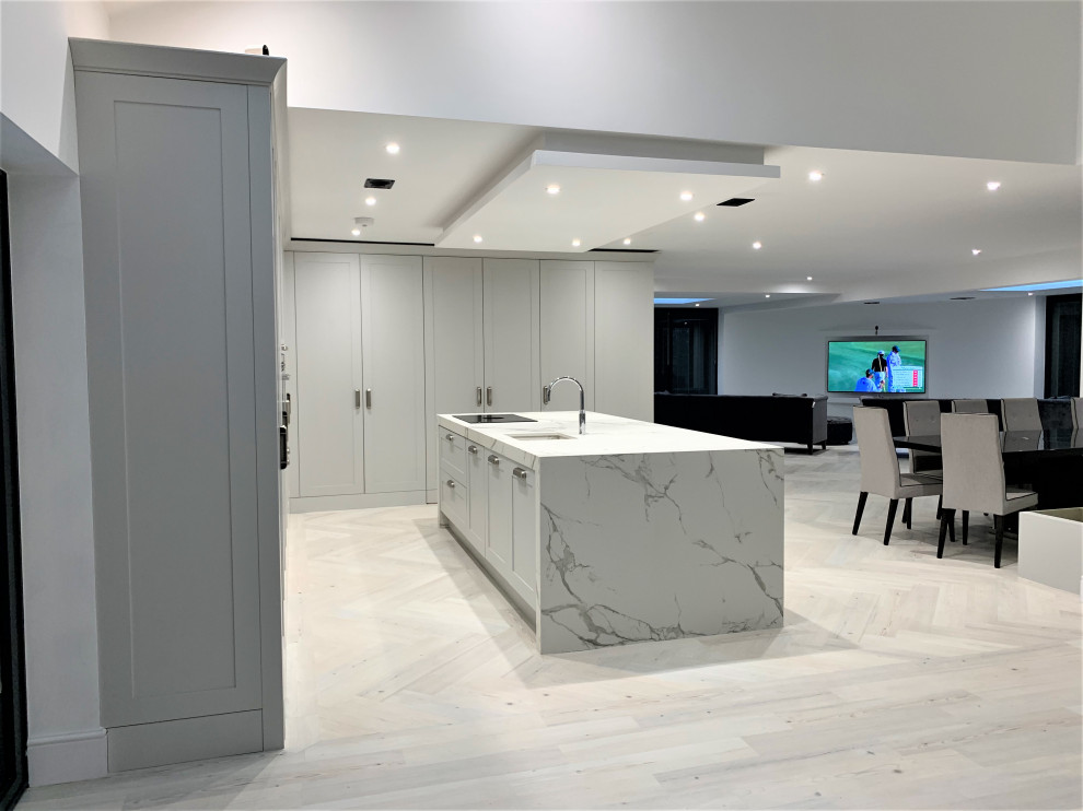 Example of a huge classic l-shaped vinyl floor open concept kitchen design in Other with a single-bowl sink, shaker cabinets, dark wood cabinets, solid surface countertops, black appliances and an island