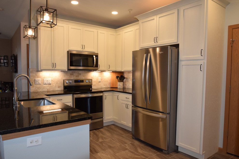 Mid-sized transitional u-shaped vinyl floor kitchen photo with a single-bowl sink, shaker cabinets, white cabinets, quartz countertops, multicolored backsplash, stone tile backsplash, stainless steel appliances, a peninsula and black countertops