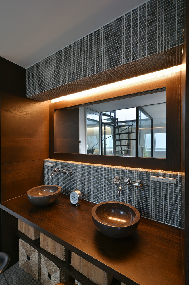 Photo of an industrial powder room in Tokyo with a console sink, blue tile, black tile and brown walls.