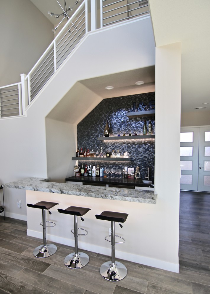 Inspiration for a mid-sized transitional single-wall seated home bar in Las Vegas with an undermount sink, open cabinets, granite benchtops, black splashback, mosaic tile splashback, medium hardwood floors, brown floor and multi-coloured benchtop.