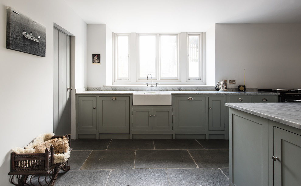 Design ideas for a mid-sized country kitchen in Gloucestershire with a farmhouse sink, shaker cabinets, marble benchtops, slate floors, with island and grey cabinets.