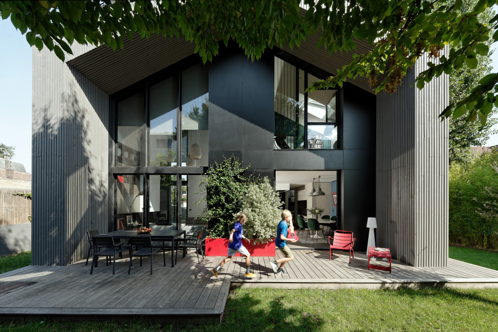 This is an example of an expansive contemporary front patio in Paris with a potted garden, decking and a roof extension.