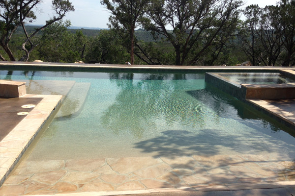 Photo of a large modern backyard custom-shaped lap pool in Austin with a hot tub and decking.