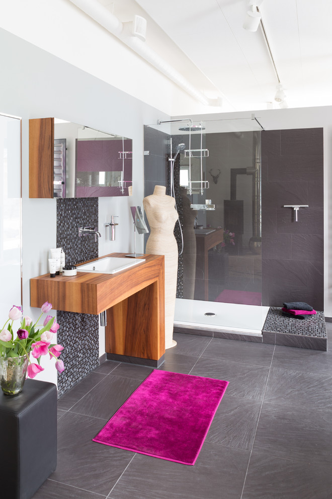 This is an example of a mid-sized contemporary 3/4 bathroom in Other with a corner shower, gray tile, grey walls, a drop-in sink, wood benchtops, grey floor, an open shower and brown benchtops.
