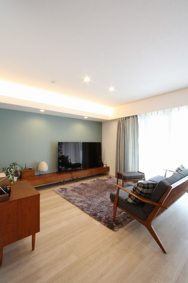 Стильный дизайн: открытая гостиная комната среднего размера в стиле модернизм с зелеными стенами, светлым паркетным полом, отдельно стоящим телевизором, бежевым полом, потолком с обоями, обоями на стенах и синим диваном - последний тренд