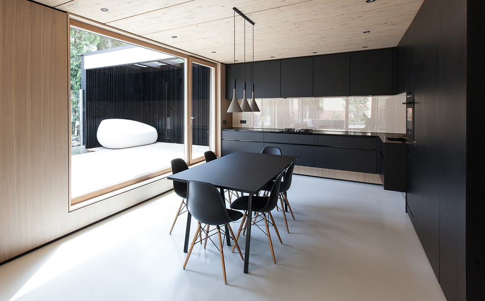 Large contemporary l-shaped eat-in kitchen in Munich with an integrated sink, flat-panel cabinets, black cabinets, beige splashback, glass sheet splashback and no island.