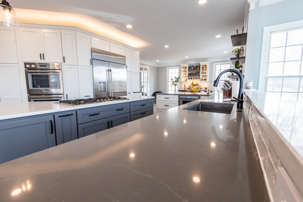 Large transitional vinyl floor and brown floor kitchen photo in Baltimore with an undermount sink, shaker cabinets, white backsplash, porcelain backsplash, stainless steel appliances, an island and white countertops