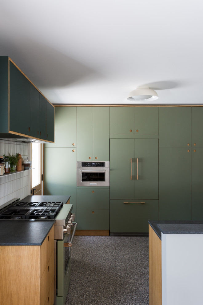 This is an example of a small midcentury l-shaped kitchen in Los Angeles with an undermount sink, flat-panel cabinets, green cabinets, granite benchtops, white splashback, ceramic splashback, terrazzo floors, with island, multi-coloured floor and black benchtop.