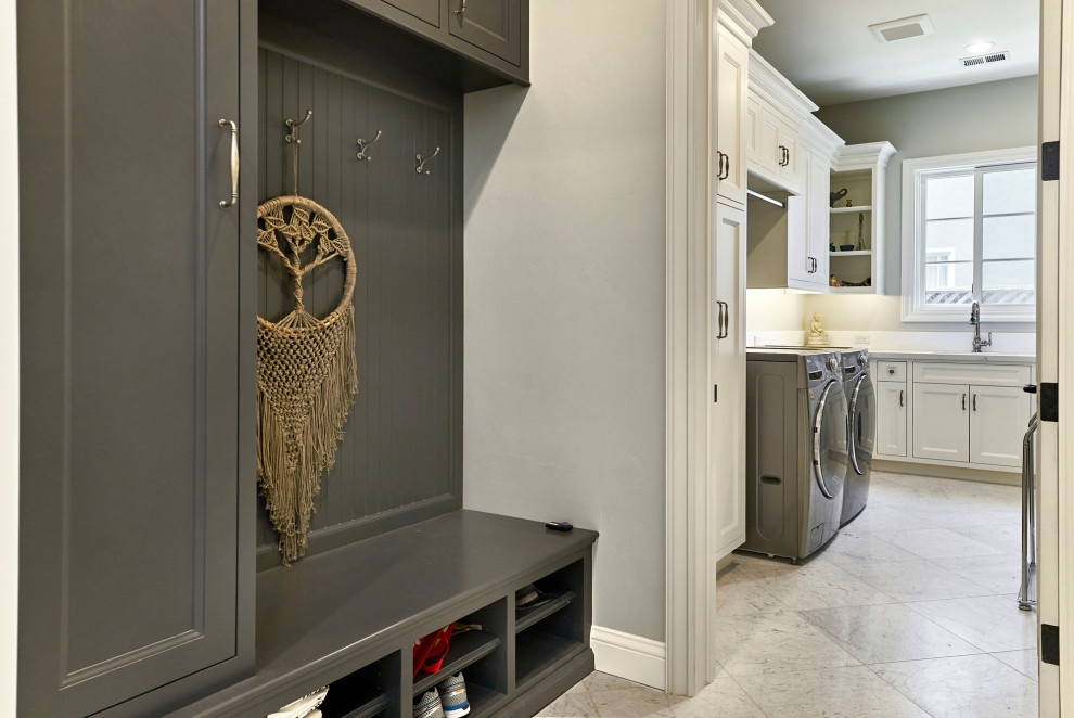 Large traditional u-shaped utility room in San Francisco with a drop-in sink, flat-panel cabinets, white cabinets, quartz benchtops, white splashback, engineered quartz splashback, grey walls, marble floors, a side-by-side washer and dryer, grey floor and white benchtop.